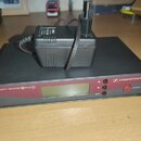 Černý bezdrátový přijímač s červeným předním panelem a LCD displejem. Na panelu jsou nápisy TRUE DIVERSITY RECEIVER EW100 G2, SET a POWER u červeného…