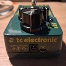 Tmavě zelený kytarový efekt s kovovým tělem a černými oválovými knoflíky. Na zadní straně je žlutý nápis tc electronic, značka napájecího vstupu 9V D…