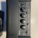 Černý kompaktní kytarový zesilovač s nápisem FLY 5 WATT MINI AMP. Na předním panelu jsou čtyři ovládací knofíky s popisky GAIN, VOLUME, EQ a DELAY, p…
