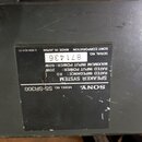 Detailní záběr na černý štítek s technickými údaji na tmavém povrchu. Štítek obsahuje nápisy SONY, MODEL NO. SS-SR300, SPEAKER SYSTEM, RATED IMPEDANC…