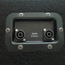 Detail zadní strany černého reproduktorového boxu s plastovým panelem. Panel obsahuje dva konektory pro kabel a bílý nápis 350W 8 Ohm. Celý panel je…