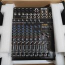 Černý mixážní pult v polystyrenovém balení v kartonu. Na horním panelu je nápis HCF F 12XR PROFESSIONAL POWERED MIXER a v pravé části PRO DSP FX. Zař…