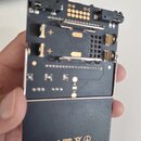 Černý elektronický modul s kovovými kontakty pro baterie a několika konektory. Na spodní části je bílý nápis PO-20 TE010AS20B made in china designed…