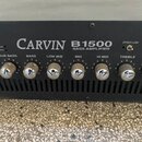 Detailní pohled na ovládací panel černého basového komba s nápisem CARVIN B1500 BASS AMPLIFIER. Panel obsahuje šest otočných kovových knobů s drážkam…