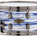 Modrý a bílý buben s vodorovnými pruhy a mramorovým vzorem. Na korpusu je umístěno oválné logo s nápisem Starclassic a menším textem TAMA DRUMS. Nást…