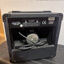 Zadní strana černého kytarového komba s texturovaným povrchem a plastovými rohy. Na horním štítku jsou nápisy INPUT POWER 230VAC-50HZ 20W MAX, varovn…