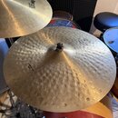 Fotografie zachycuje dva mosazné činely v rámci bicí sady. Přední činel má výrazně kladivovaný povrch a nápisy K ZILDJIAN, Custom Dark a 22" MEDIUM T…