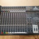 Šedý 12kanálový mixážní pult s černým rámem. Na horním panelu je nápis PENEY DESIGNED AND MADE IN U.S.A. UNITY SERIES 2002-12 RQ a dále 12 CHANNEL PR…