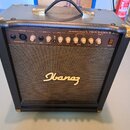 Černý akustický kytarový kombozesilovač s texturovaným povrchem, zlatými kovovými rohy a úchytem. Na předním panelu je nápis 25W ACOUSTIC AMPLIFIER T…