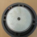 Fotografie znázorňuje zadní stranu černého reproduktorového membrány s kovovým magnetem stříbrné barvy. Na horní části jsou vidět dva zlaté připojova…
