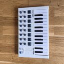 Bílá MIDI klaviatura s 25 klávesy, umístěná na dřevěné podlaze. Na horní části je nápis ARTURIA a v dolní části model MINILAB mkII. Ovládací panel ob…