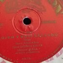 Detail červeného štítku jedné strany vinylové desky. Na štítku je nápis PLUJEM V NOCI SÁZAVOU, pod ním styl Tango a text Slova: Adam Adam, Zpívá OLDR…
