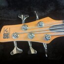 Detail hlavy basové kytary z dřeva s přirozeným nažlutlým odstínem. Na hlavě je umístěno logo „SDGR“ a nápis „SOUNDGEAR BY IBANEZ“. Nástroj má čtyři…