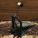 Černý basový pedál s kovovým šlapadlem a řetězovým přenosem. Na šlapadle je vyryt nápis "Double Pedal". Konstrukce je z černého kovu s viditelnými šr…