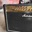 Černý kytarový kombo zesilovač značky Marshall. Na horním ovládacím panelu je nápis JCM 2000 - 60W a vpravo označení TS TRIPLE S. Jsou zde vidět ovlá…