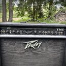 Černý kytarový kombo zesilovač značky Peavey. Na horním ovládacím panelu je nápis TNT a logo Peavey, dále jsou zde ovladače s popisky jako INPUTS, SH…