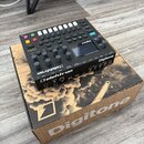 Černý digitální syntetizátor Elektron Digitone položený na originální krabici s nápisem Digitone. Na horním panelu jsou vidět bílá tlačítka, barevné…