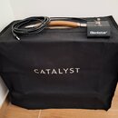 Černý textilní kryt na kombo zesilovač s bílým nápisem CATALYST. Na krytu leží černý jeřábí spínač s nápisy CHANNEL a Blackstar, k němu připojený čer…