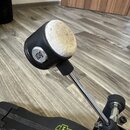 Detailní záběr na pedál s kovovou tyčí a černým plastovým knoflíkem, který má na horní části bílou, opotřebovanou houbovou nebo plstěnou vrstvu. Na b…