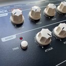 Detailní pohled na ovládací panel černého elektronického zařízení s bílými plastovými oválovými knoflíky. Na panelu jsou bílé nápisy KICK lannet, SOU…