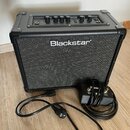 Černý kytarový kombo zesilovač s nápisem Blackstar na přední textilní mřížce. Horní ovládací panel obsahuje několik otočných potenciometrů a přepínač…