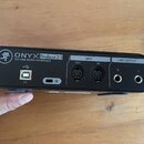 Zadní strana černé USB zvukové karty s nápisem ONYX Producer 2.2 a 2x2 USB AUDIO INTERFACE. Zařízení obsahuje USB port s označením 2.0, dva MIDI kone…