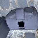 Černý textilní pouzdro na hudební nástroj s rukojetí a kapsou na zipu. V dolní části je vidět čtvercový otvor pro přístup k ovládacím prvkům. Povrch…
