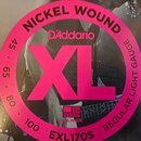 Detailní záběr na obal strun s nápisy NICKEL WOUND, D'Addario a velkým růžovým označením XL. Na obalu je dále uveden text REGULAR LIGHT GAUGE, hodnot…