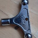 Kovový klíč na ladění bubnů v chromovaném provedení. Na povrchu je vyražen nápis Pearl. Předmět vykazuje známky používání v podobě drobných škrábanců…