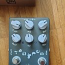 Šedý efekt pedál s šesti bílými oválnými knoflíky. Na pedálu jsou ručně psané popisky Treble, Mid, Bass, Boost, Vol a Dist, nápisy OUTPUT a INPUT, v…