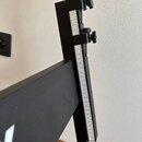 Detailní záběr na černý kovový stojan s vertikální stupnicí. Na bílém proužku je vidět černé číslování od 0 do 28. Mechanismus obsahuje dva šrouby s…