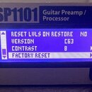 Detailní pohled na přední panel stříbrného zařízení s nápisem GSP1101 Guitar Preamp / Processor. Uprostřed je modrý displej s texty RESET LVLS ON RES…