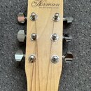Záběr na hlavu akustické kytary zC světlého dřeva. V horní části je nápis „Norman“ a pod ním text „Est. 1972 Québec, Canada“. Nástroj má šest chromov…