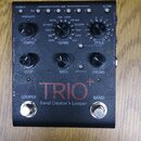 Černý efekt pedál s nápisem TRIO+ a doplňkem Band Creator+ Looper. Zařízení má tři otočné knoflíky s popisky AUDIOLASTIC, TEMPO a STYLE, dále tři ovl…
