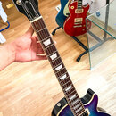 Elektrická kytara typu Les Paul s tmavě modrým gradientem a zlatými potenciometry a hardwarem. Na hlavě hmatníku je bílý nápis Gibson a modelové ozna…