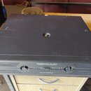 Černý výkonový zesilovač v rackovém provedení. Na předním panelu je bílý nápis AMERICAN AUDIO, pod ním text PROFESSIONAL POWER AMPLIFIER a ve spodní…