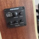 Detail ovládacího panelu předzesilovače Fishman Isys+ s černým plastovým krytem, který je osazen do dřevěného těla nástroje. Panel obsahuje nápisy FI…