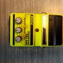 Žlutý efekt pedál s nápisy METAL MANIAC a FX58. Na zařízení jsou tři ovládací knoflíky s popisky DISTORTION, PRESENCE a LEVEL, červená kontrolka a zn…