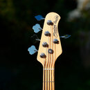 Detail hlavy basové kytary z přírodního dřeva. Na hlavě je nápis Sterling Ray 35 by MUSIC MAN. Jsou vidět čtyři chromované ladičky a čtyři kolíky str…