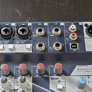 Šedý mixážní pult s ovládacími prvky a konektory. Na horním panelu jsou vstupy označené jako MIC 1, MIC 2, LINE 3/4, LINE 5/6 a LINE 7/8, dále výstup…