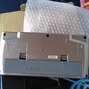Fotografie zachycuje spodní stranu stříbrného elektronického hudebního zařízení. Na bílém štítku je uveden kód J101204 a vedle něj nápis YAMAHA. V do…