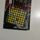 Fotografie znázorňuje originální krabici od kontroléru Novation Launchpad Mini. Na obalu je zobrazen produkt s podsvícenými padovými tlačítky v žluté…