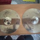Dvě mosazné činely položené na dřevěném povrchu. Levý činel nese nápisy Z Custom, Zildjian a ručně psaný text Dune Fast 14"/20. Pravý činel má nápis…
