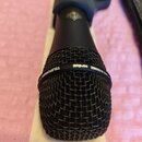 Černý dynamický mikrofon s kovovou síťkou. Na kroužku kolem hlavy je bílý nápis TELEFUNKEN DYNAMIC cardioid. Povrch těla a síťky vykazuje mírné známk…