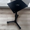 Černý skladací stojan s plochou čtvercovou deskou a trojnožkou. Konstrukce je vyrobena z černého kovu s matným povrchem. Na desce jsou vidět drobné p…