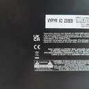 Detailní pohled na zadní černou plastovou část zařízení s několika nálepkami a nápisy. Horní bílá nálepka obsahuje text VYPYR X3 230EB a SERIAL NUMBE…
