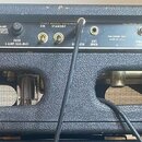 Zadní strana kytarového komba v černém texturovaném potahu s kovovými rohy. Horní kontrolní panel obsahuje nápisy FENDER MUSICAL INSTRUMENTS, FULLERT…