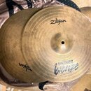 Dvě mosazné činely s viditelným opotřebením a patinou. Na předním činelu je nápis Zildjian a stylizovaný modrý text SPECIALITY Bionze. Povrch činelů…