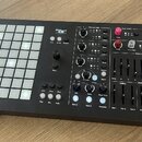 Černý hybridní syntetizátor s nápisem Medusa a podtitulem Dreadbox & Polyend Hybrid Synthesizer. Na levé straně se nachází mřížka bílých podsvícených…