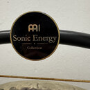 Detailní záběr na kulatý černý štítek s gold okrajem. Na štítku je zlaté logo MEINL a nápisy Sonic Energy a Collection. Štítek je přilepen na černý k…